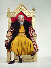 King, royalty and angry man on throne in studio isolated on a gray background mockup.Thinking, medieval and annoyed senior male, upset leader or frustrated ruler with crown sitting on golden seat.