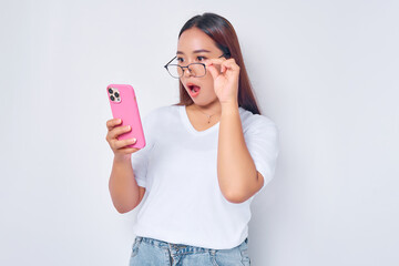 Beautiful surprised Asian girl wearing casual white t-shirt holding and looking smartphone, reading...