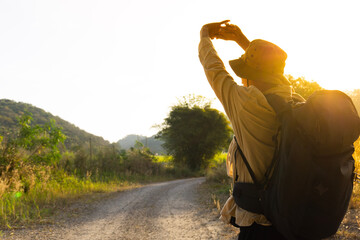 Rear view of a young backpacker male stretching his arm while hiking into the mountains in the...