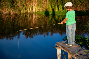 Boy fisherman with a fishing rod on the shore of the lake, child vacations. Happy boy go fishing on the river.