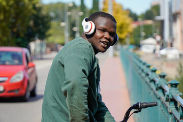 portrait of black boy from africa on a bike with headphones looking at camera