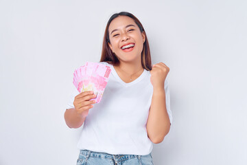 Excited young blonde woman girl Asian wearing casual white t-shirt holding money rupiah banknotes...