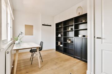 a room with a desk, chair and bookcases on the wall next to an open door that leads to a window © Casa imágenes