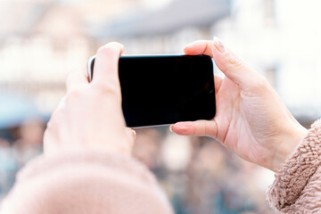 A Cheerful woman taking selfies on a smartphone, talking on the phone. A curly brunette lady in a jacket and orange scarf smiling and traveling in Europe.