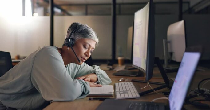 Night, call center or senior woman tired, exhausted or burnout in workplace, overworked or stress. Dark, female employee or consultant with headset, late night or customer service agent with headache