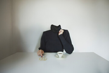 headless surreal woman draws a sad face on the table with coffee, concept of communicating one's...