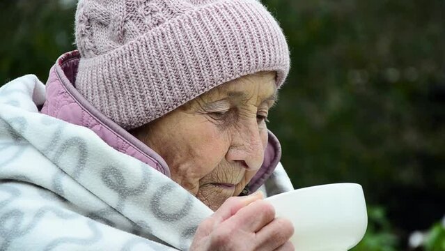 The face of an old woman. A woman wrapped herself in a blanket during the war. War in Ukraine. Wrinkled face close-up. Sad Ukrainian woman. Stop war. Peace concept. Winter in Ukraine during the war.
