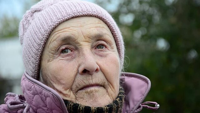 An old woman during the war. The face of an old grandmother. Wrinkled face close-up.Ukrainian refugees. Destructive war in Ukraine. Peace concept. Russian aggression. Ukrainian woman during the war.