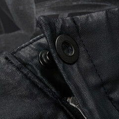 Metal fastener on avant-garde black waxed pants