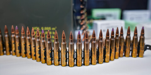Bandolier or ammo belt with machine gun rounds at display at weapons fair, closeup detail - obrazy, fototapety, plakaty