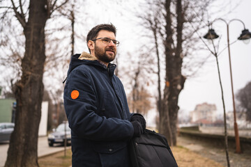 One bearded caucasian man with laptop bag standing outdoor in winter