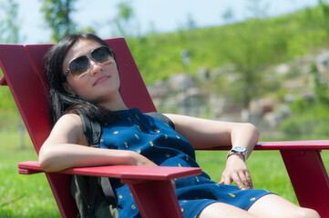 a happy chinese woman sitting on an adirondack chair
