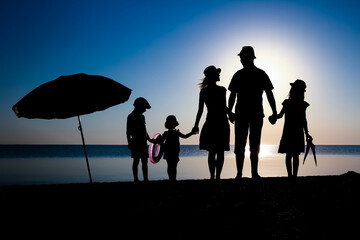 Fototapeta na wymiar A Happy family by the sea at sunset in travel silhouette in nature