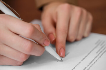 Woman signing documents on brown background, closeup