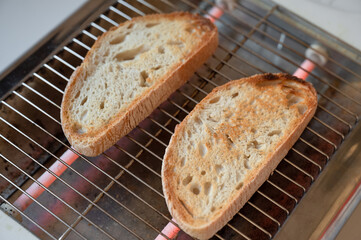 Toaster heating two bread slice in a white table of the kitchen