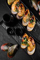 Baked mussels with cheese on black concrete background