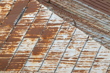 Rusty metal roof of an old house with cracked paint