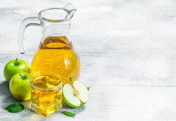 Juice and fresh apples in a glass jar with slices of apples.
