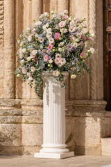 Naklejka premium Luxury wedding floral decorations at the entrance of Ostuni church. Wedding celebrations in south Italy. Big bouquets of colorful flowers.