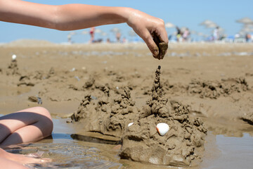 Boy builds a sand fortress on the beach by the sea