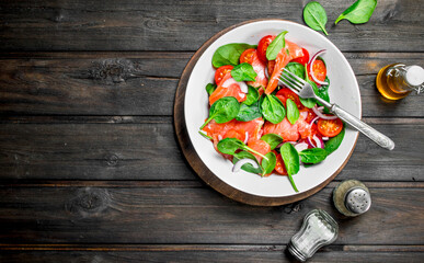 Fish salad. Salad with slices of salmon, tomatoes and spinach with lime juice.