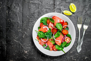Fish salad. Salad with slices of salmon, tomatoes and spinach with lime juice.