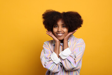 Obraz na płótnie Canvas Portrait of smiling African American woman on orange background