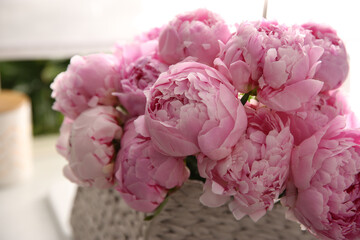 Basket with beautiful pink peonies in kitchen, closeup