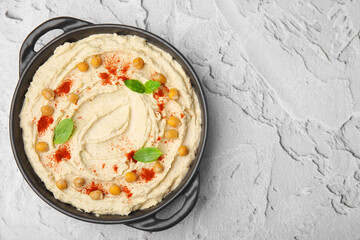 Delicious hummus with chickpeas and paprika on white textured table, top view. Space for text