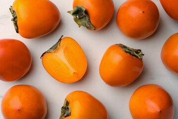 Delicious ripe persimmons on white table, flat lay
