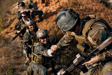 command rangers soldiers during the military operation. soldiers climbing on mountain, one of them...