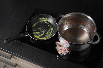 Dirty pot and frying pan on cooktop in kitchen, above view