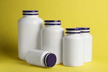 Many closed medicine bottles on yellow background