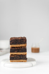 A stack of fudgy brownies, fudgy caramel brownies with a cookie crust, stack of brookies, thick...