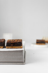 Fudgy caramel brownies with a cookie crust on a silver tray, thick brownie bars