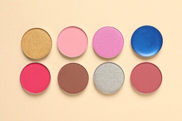 Different beautiful eye shadows on beige background, flat lay