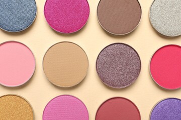 Different beautiful eye shadows on beige background, flat lay