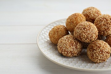 Delicious sesame balls on white wooden table, closeup. Space for text