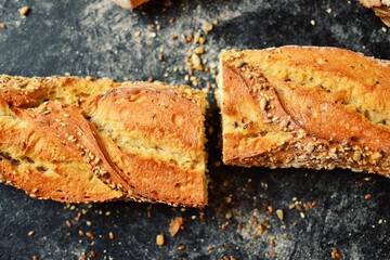 Bakery products in a wicker basket. Round homemade bread, long loaf with seeds, vegan bread without yeast. Wooden background