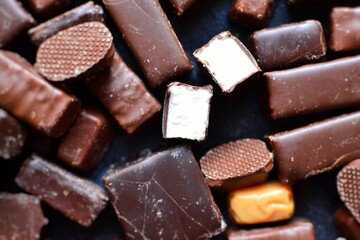 Assortment of chocolates. Candies on a dark bluish background. Top view place for text. Dark chocolate. Chocolate bars.