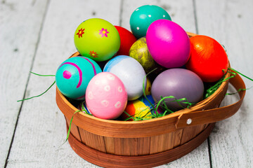 Basket with painted colorful easter eggs on wooden table