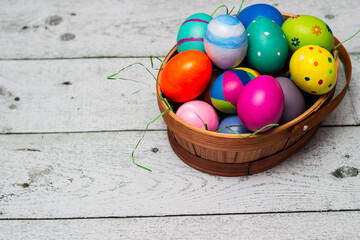 Basket with painted colorful easter eggs on wooden table