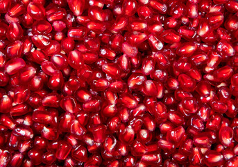A close-up with many red pomegranate seeds