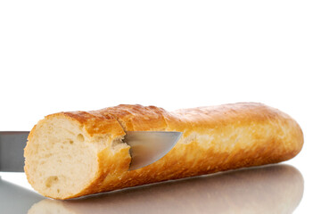 One half of fresh aromatic baguette with metal knife, macro, isolated on white background.