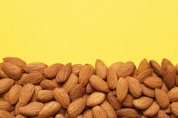 Delicious raw almonds on yellow background, flat lay. Space for text
