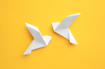 Origami art. Colorful handmade paper birds on yellow background, flat lay