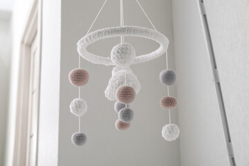 Modern baby crib mobile near beige wall in room, low angle view