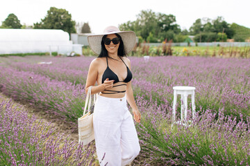 fashion outdoor photo of beautiful woman with dark hair posing in bloomig lavender field on sunset