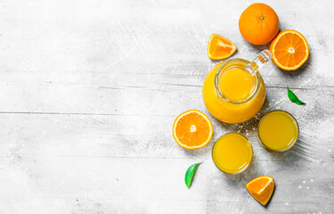 Orange juice in the pitcher and slices of fresh oranges. - obrazy, fototapety, plakaty