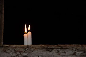 Three candles stand on a broken window of an old residential building, view from the street through...